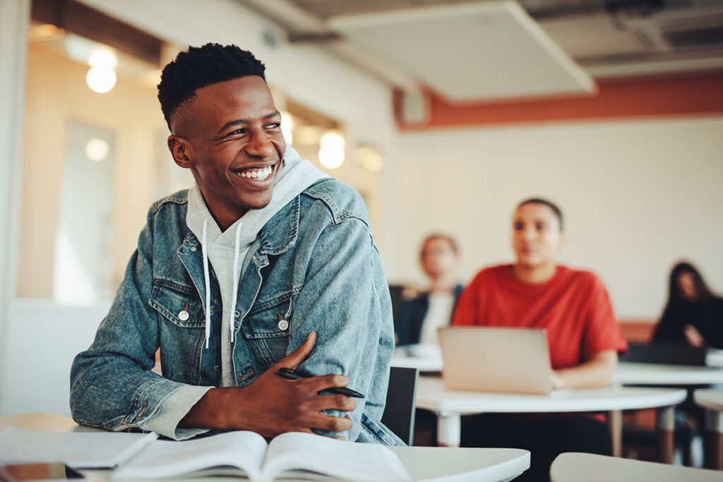 a young person smiles away from the camera while sitting in a classroom thinking about personality disorders