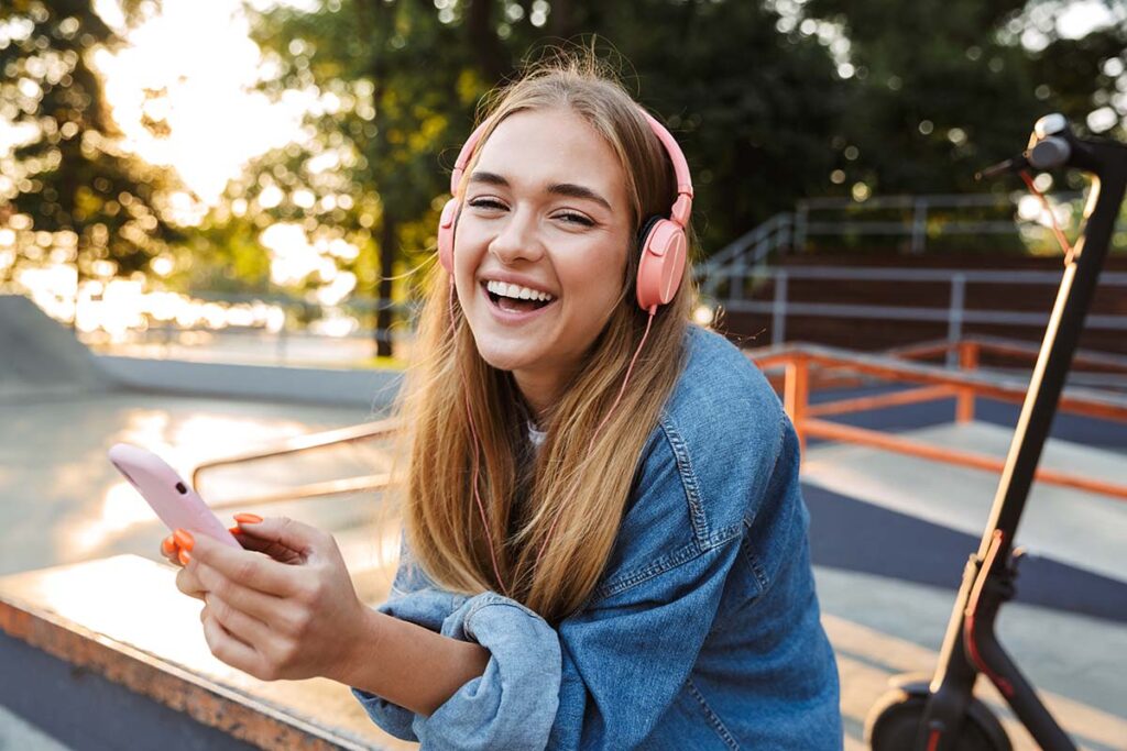 a teen with headphones on next to a scooter and holding a phone at a skate park learns about personality disorders