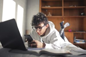 a teen looks at a computer and phone while looking up an ADHD Treatment Program