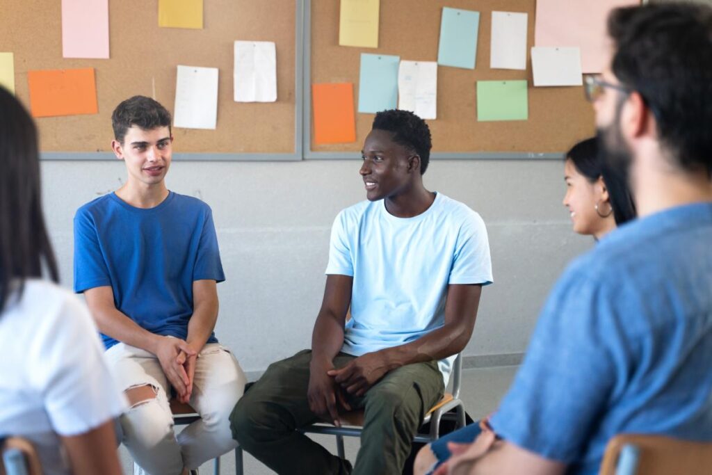 a group of young people talk to each other in a group therapy session for anxiety