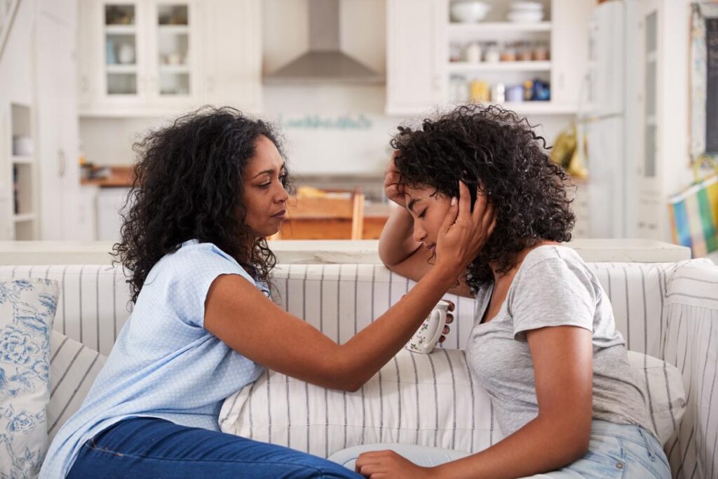 a young person is comforted by their parent on a couch during depression treatment