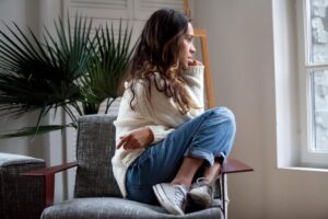 a young person looks out a window showing common anxiety symptoms