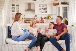 a family sits on a couch smiling and laughing while talking about family therapy program