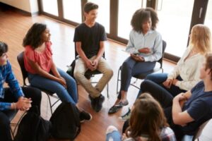 a group of young adults sit in a circle during group therapy