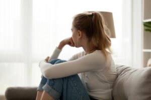 a teen sits on a couch and looks out a window wondering about ocd treatment