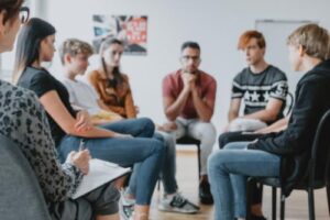 a group of teens sit in a circle during mental health treatment for teens