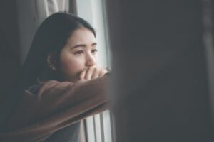 a teen looks out a window wondering about getting trauma treatment