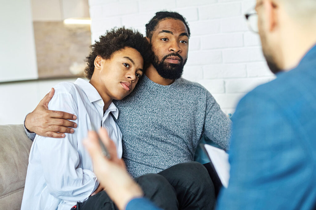 father and son with counselor in family therapy for teens